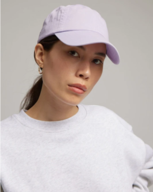 Femme en pull gris qui porte une casquette violette